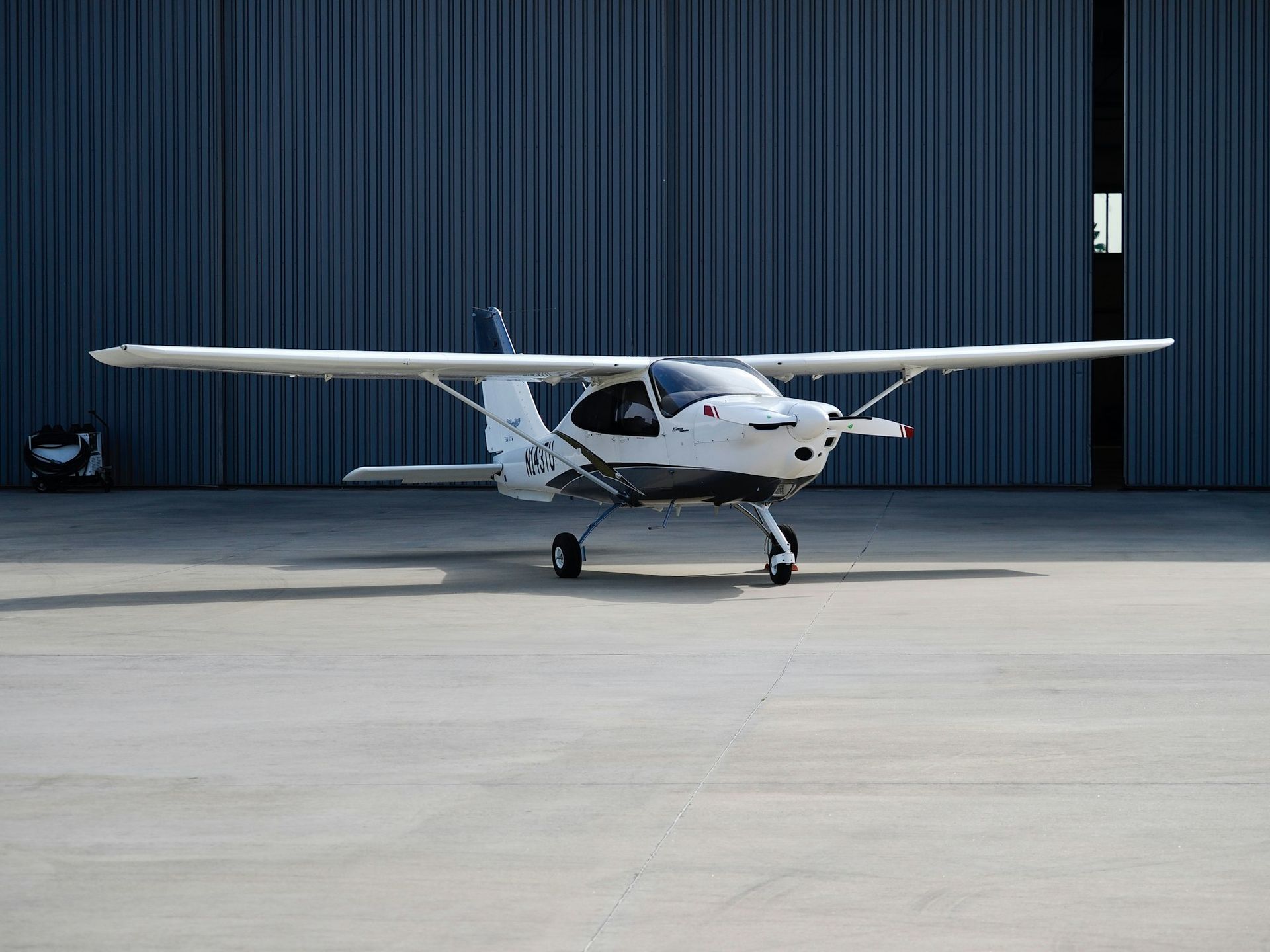 Monomoteur blanc devant la porte d'un hangar