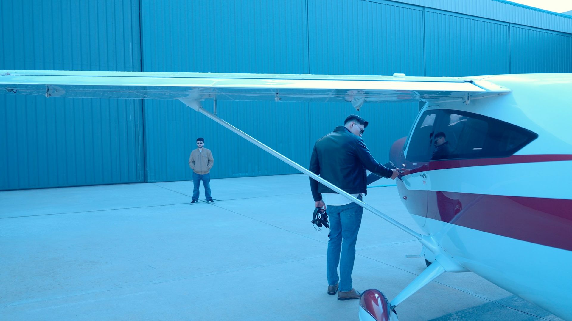 Deux personnes ouvrant la porte d'un monomoteur dans un hangar